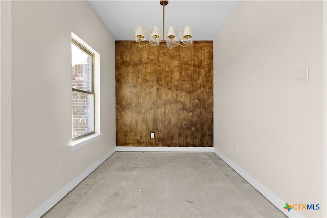 unfurnished dining area with concrete flooring and a chandelier