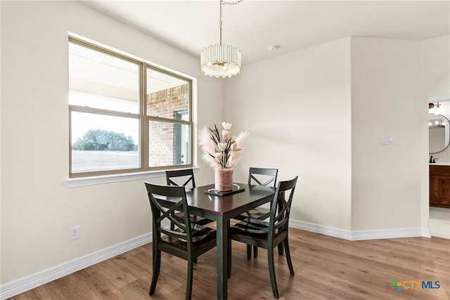 dining area featuring wood finished floors, baseboards, and an inviting chandelier