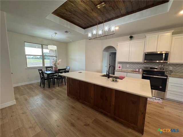 kitchen featuring tasteful backsplash, white cabinetry, an island with sink, and wooden ceiling