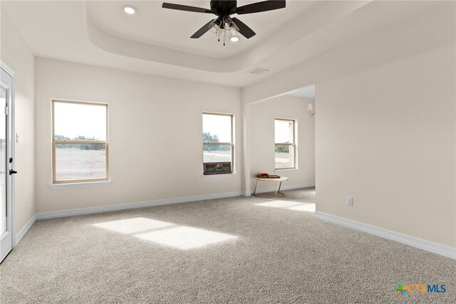 unfurnished bedroom with ceiling fan with notable chandelier and a tray ceiling