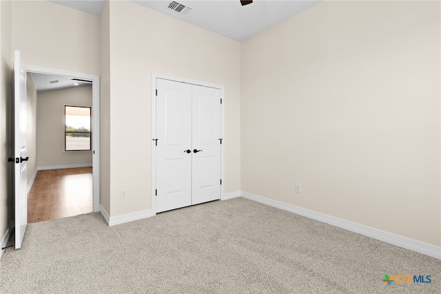 unfurnished bedroom featuring lofted ceiling, carpet flooring, visible vents, baseboards, and a closet