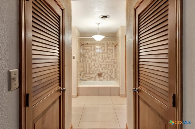 interior space featuring tile patterned flooring, tiled shower / bath combo, and a textured ceiling