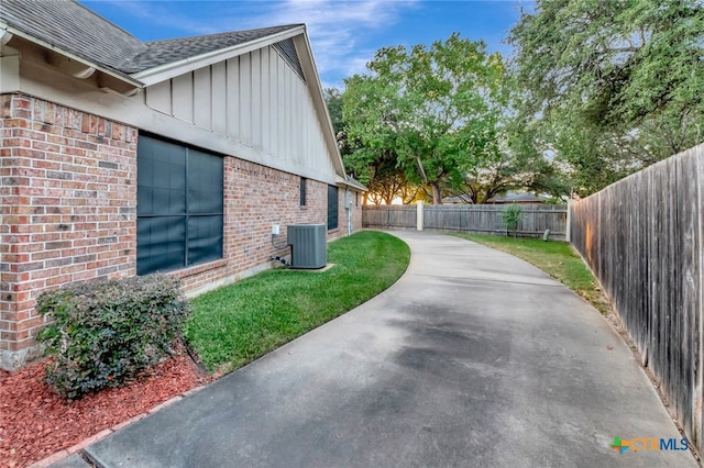 view of side of property featuring a lawn, cooling unit, and a patio area