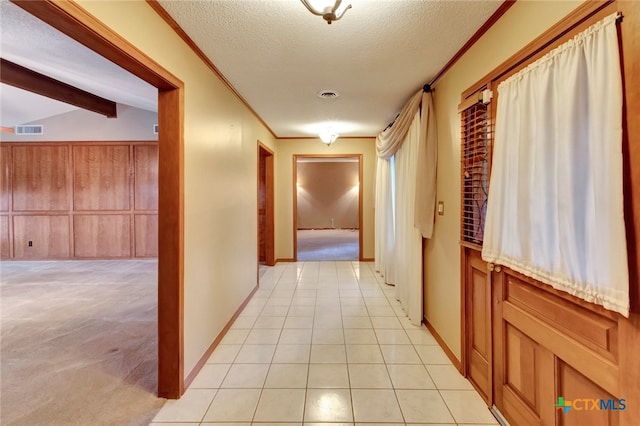 hall featuring lofted ceiling with beams, crown molding, light colored carpet, and a textured ceiling