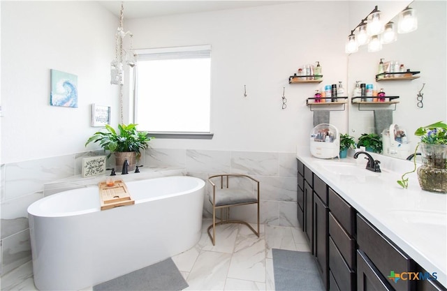 3810 Twilight Dr, Temple, TX 76502 - bathroom featuring tile walls, marble look tiles, double vanity, a freestanding bath, and wainscoting