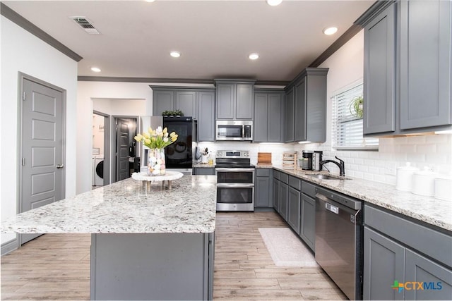 3810 Twilight Dr, Temple, TX 76502 - kitchen featuring appliances with stainless steel finishes, crown molding, gray cabinets, light stone countertops, and a kitchen island