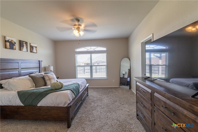 bedroom featuring ceiling fan, light carpet, and multiple windows