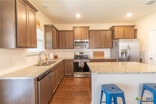 kitchen with light stone counters, sink, and appliances with stainless steel finishes