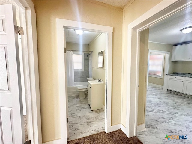 hallway with marble finish floor, baseboards, and a sink