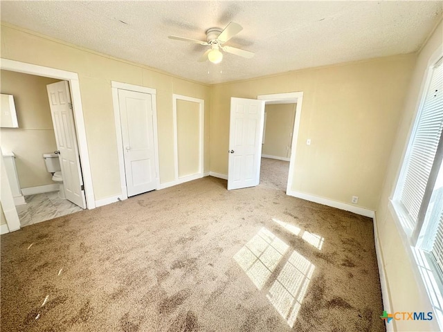 unfurnished bedroom featuring connected bathroom, carpet, baseboards, and a textured ceiling