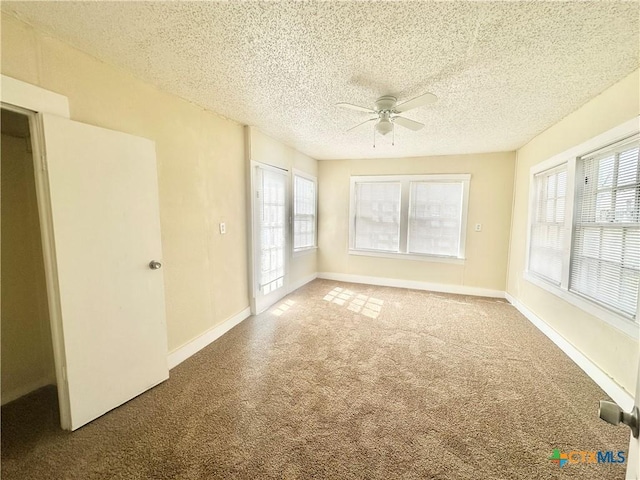 carpeted empty room featuring a ceiling fan, baseboards, and a textured ceiling