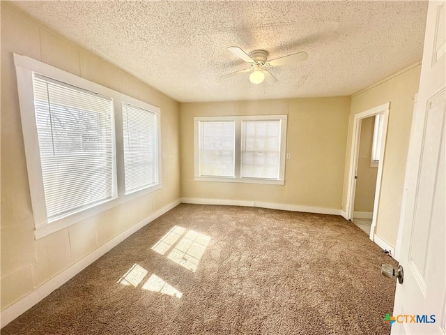 unfurnished room with a textured ceiling, carpet, baseboards, and ceiling fan