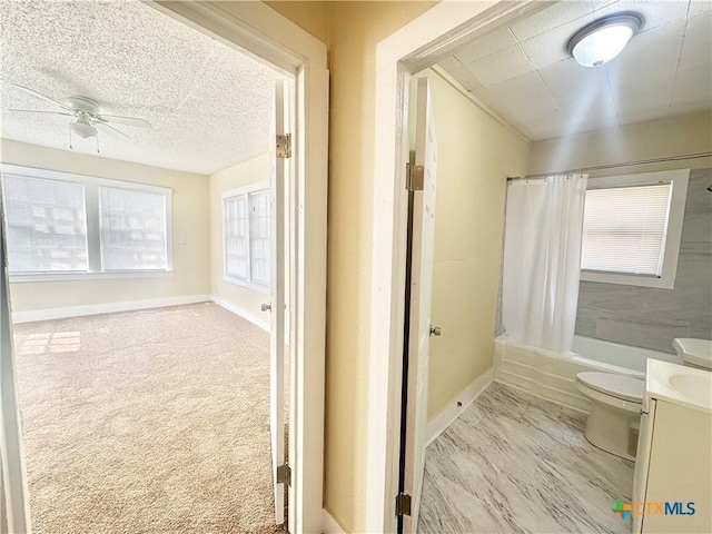 bathroom featuring shower / bath combo with shower curtain, toilet, a textured ceiling, baseboards, and vanity