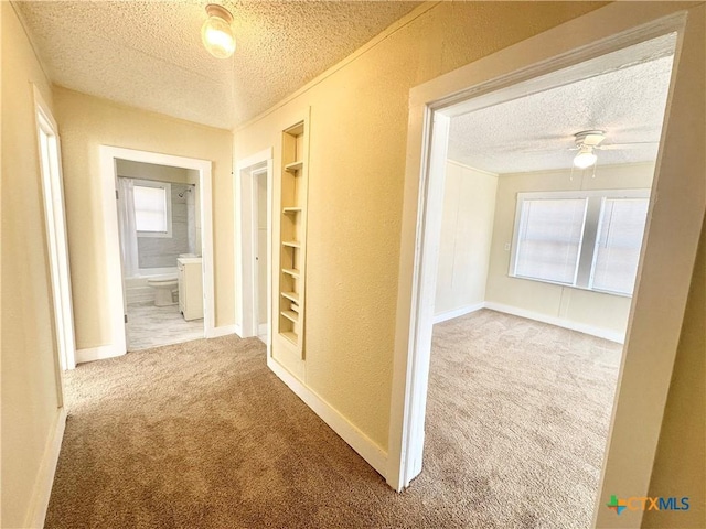 hallway featuring baseboards, carpet, and a textured ceiling