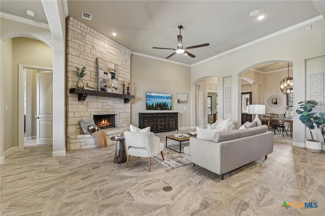 living area featuring baseboards, visible vents, ornamental molding, a fireplace, and ceiling fan with notable chandelier