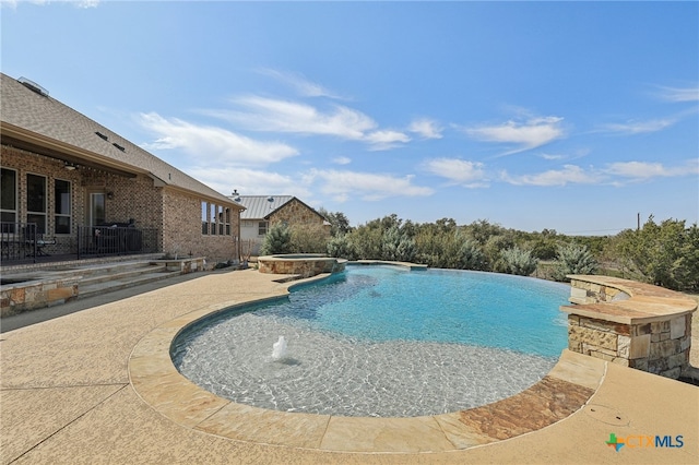 view of swimming pool featuring a pool with connected hot tub and a patio