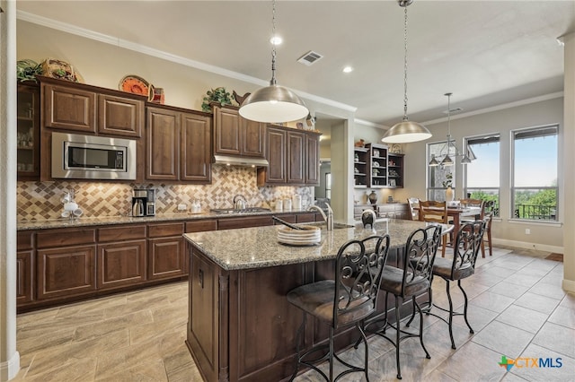 kitchen with a sink, visible vents, appliances with stainless steel finishes, backsplash, and crown molding