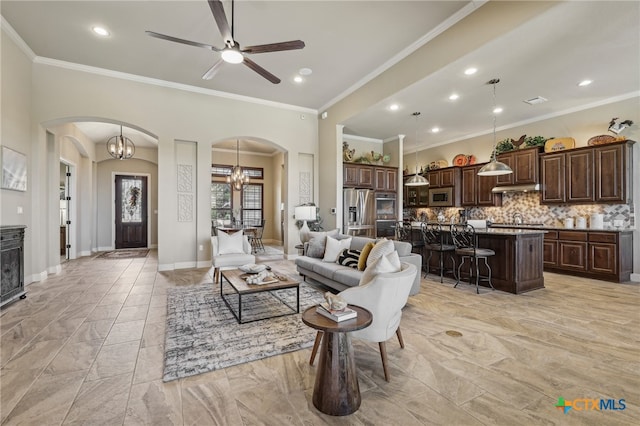 living area with arched walkways, crown molding, and baseboards