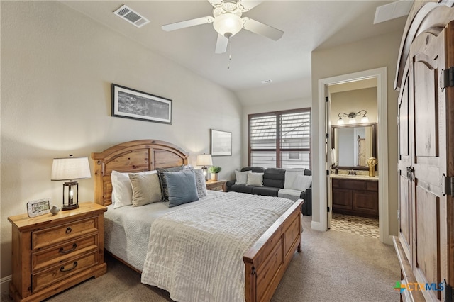 bedroom with light colored carpet, visible vents, baseboards, vaulted ceiling, and ensuite bath