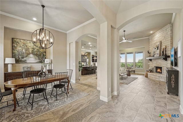 dining area with a stone fireplace, ornamental molding, a ceiling fan, and baseboards