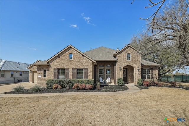 view of front facade featuring brick siding, a front lawn, and fence