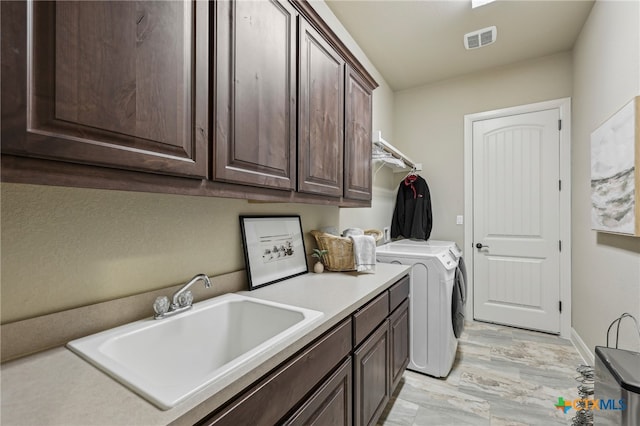 washroom with a sink, visible vents, baseboards, cabinet space, and washer and clothes dryer