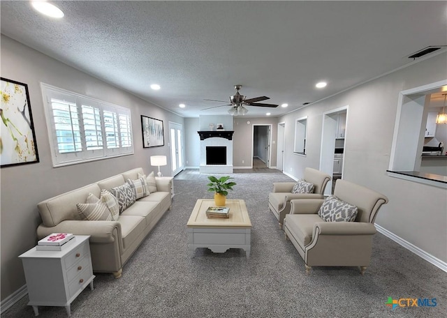 living room featuring a textured ceiling, ceiling fan, and carpet