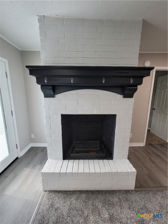 details with a brick fireplace, a textured ceiling, and hardwood / wood-style floors