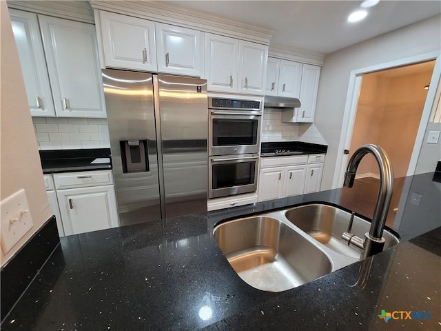 kitchen featuring appliances with stainless steel finishes, white cabinets, backsplash, and sink