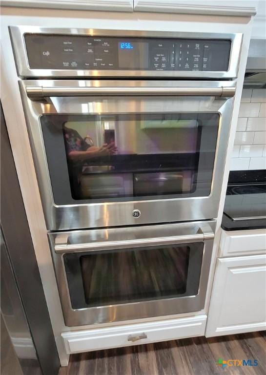 interior details featuring stainless steel double oven and dark hardwood / wood-style floors