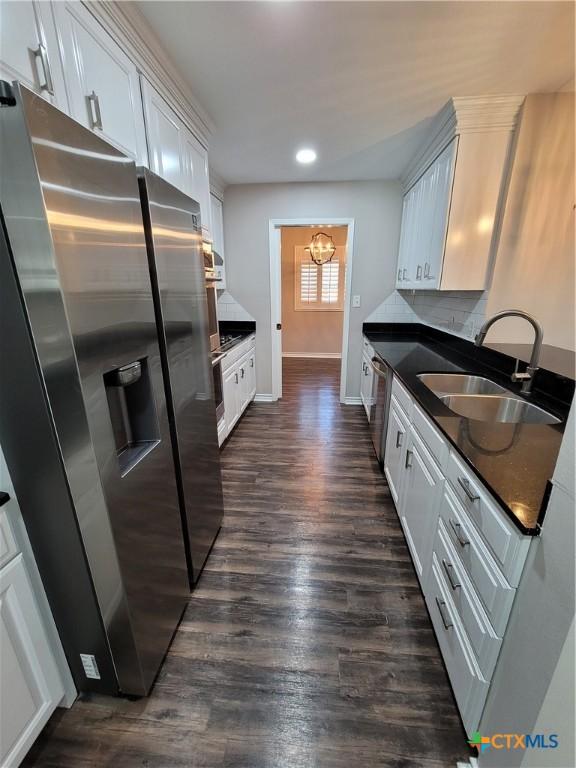 kitchen featuring an inviting chandelier, backsplash, white cabinetry, appliances with stainless steel finishes, and sink