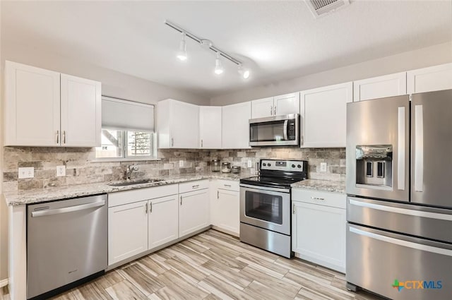 kitchen featuring appliances with stainless steel finishes, sink, white cabinets, and light stone counters