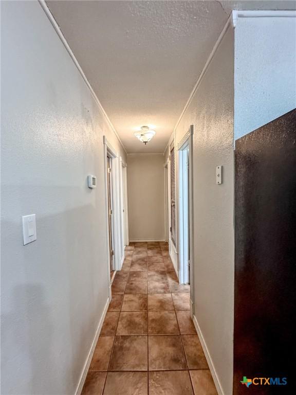 hallway featuring dark tile patterned floors and ornamental molding