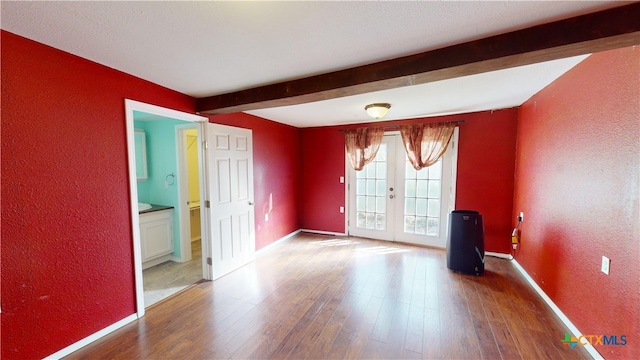 702 E Anaqua Ave, Victoria, TX 77901 - empty room featuring french doors, a textured wall, beamed ceiling, and wood finished floors