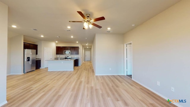 kitchen with ceiling fan, stainless steel appliances, a kitchen island with sink, and light wood-type flooring