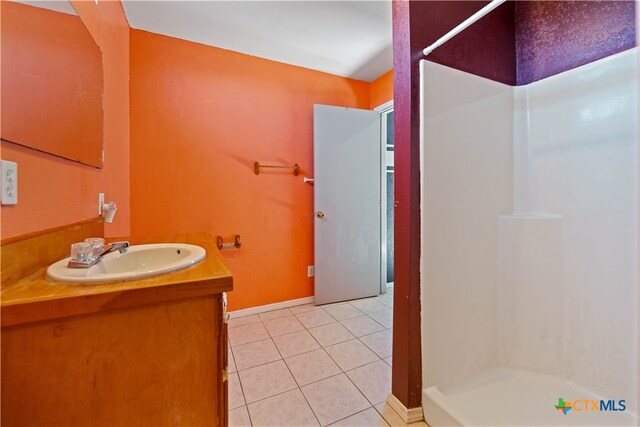 bathroom with a shower, vanity, and tile patterned floors