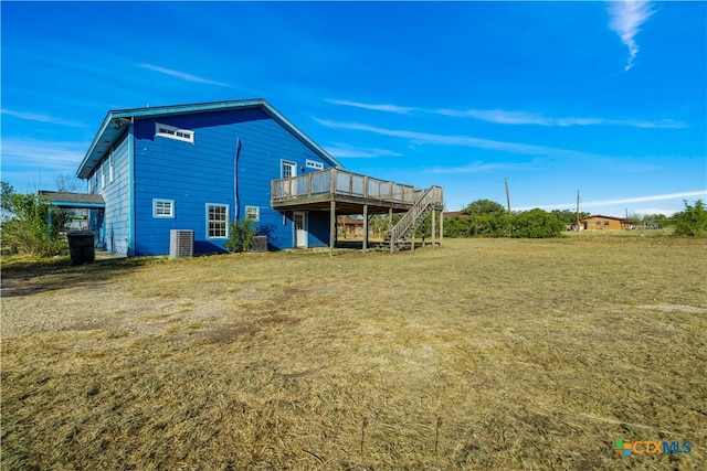 rear view of property with central AC unit, a wooden deck, and a yard