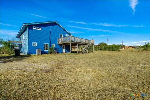 rear view of property with central AC unit, a wooden deck, and a yard