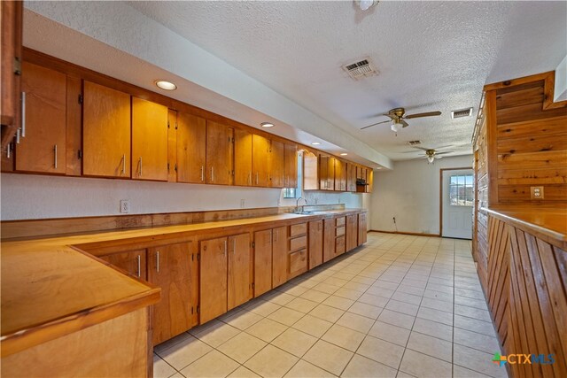 kitchen with ceiling fan, a textured ceiling, light tile patterned floors, and sink