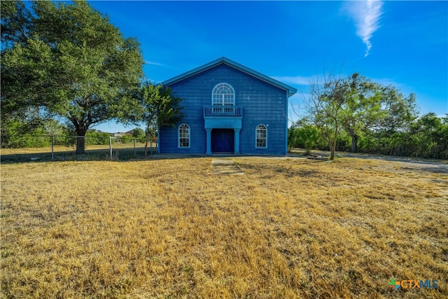 rear view of property featuring a balcony and a yard