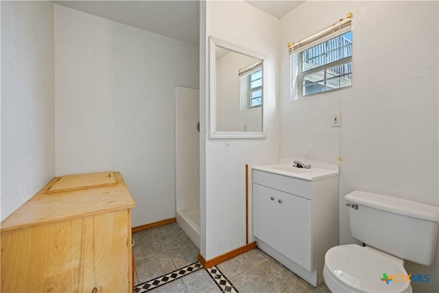 bathroom featuring a shower, tile patterned flooring, vanity, and toilet