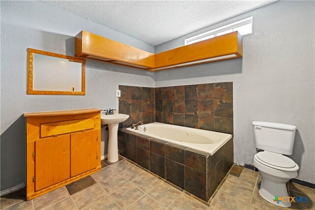 bathroom with tile patterned floors, a textured ceiling, toilet, and a relaxing tiled tub