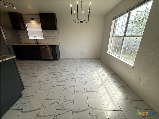 unfurnished dining area with marble finish floor, baseboards, a chandelier, and a sink