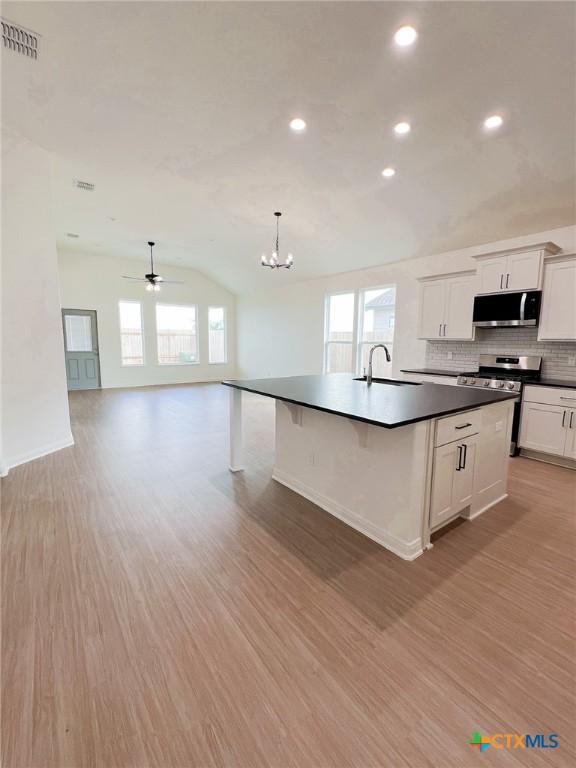 116 Raindance Ct, Victoria, TX 77904 - kitchen with appliances with stainless steel finishes, dark countertops, light wood finished floors, backsplash, and a chandelier