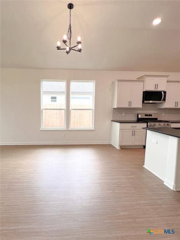 116 Raindance Ct, Victoria, TX 77904 - kitchen featuring stainless steel appliances, dark countertops, a chandelier, decorative backsplash, and light wood-type flooring