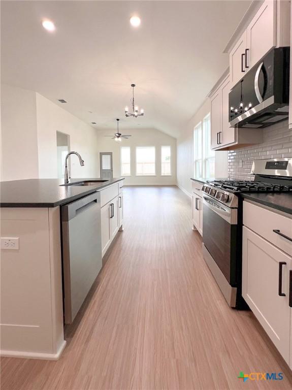 116 Raindance Ct, Victoria, TX 77904 - kitchen featuring stainless steel appliances, dark countertops, lofted ceiling, light wood-type flooring, and a chandelier
