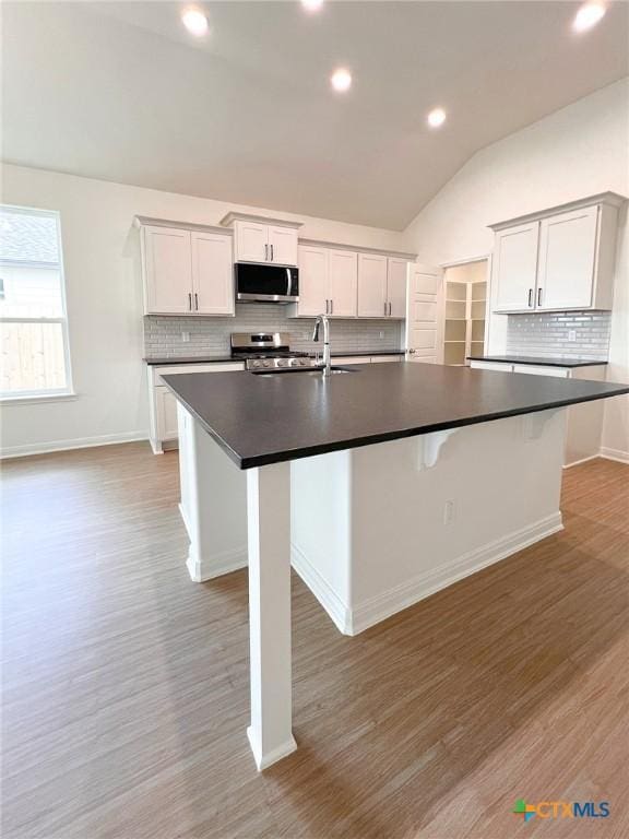 116 Raindance Ct, Victoria, TX 77904 - kitchen featuring stainless steel appliances, dark countertops, a large island, decorative backsplash, and lofted ceiling