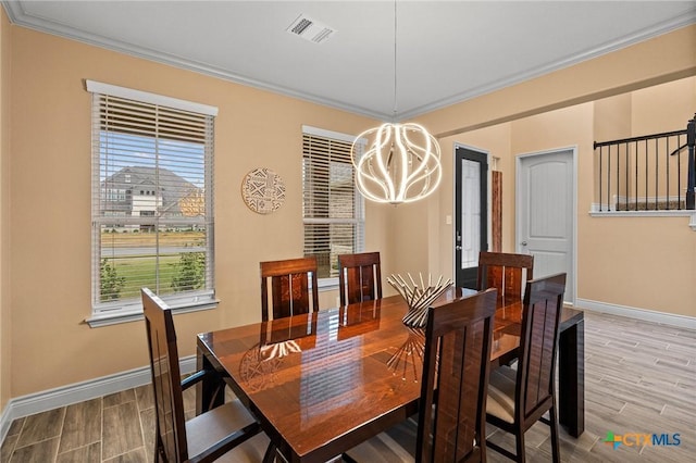 dining room with a notable chandelier, a healthy amount of sunlight, wood-type flooring, and crown molding