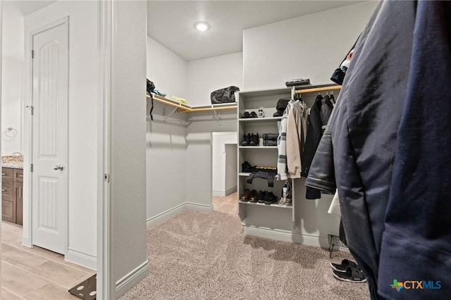 walk in closet with light colored carpet