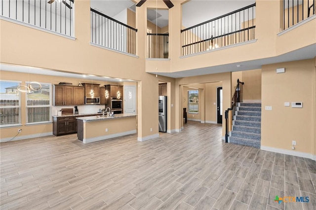 living room featuring light wood-type flooring, a towering ceiling, and plenty of natural light